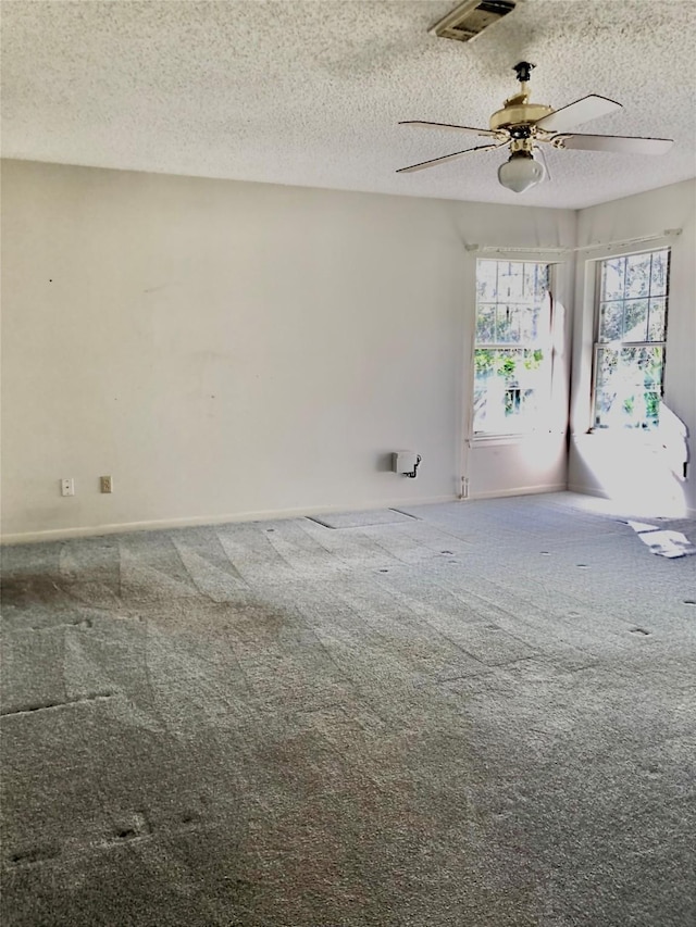 carpeted spare room featuring ceiling fan and a textured ceiling