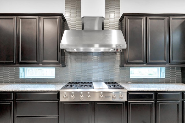 kitchen featuring decorative backsplash, wall chimney range hood, and stainless steel gas stovetop