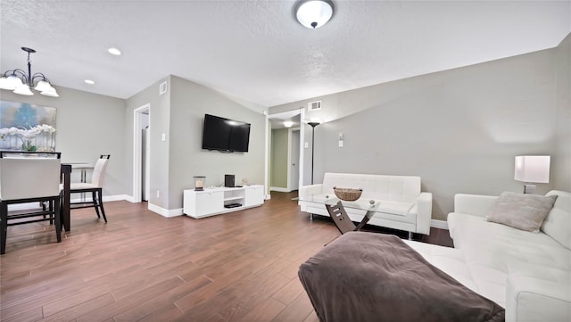 living room featuring hardwood / wood-style floors, a textured ceiling, and an inviting chandelier