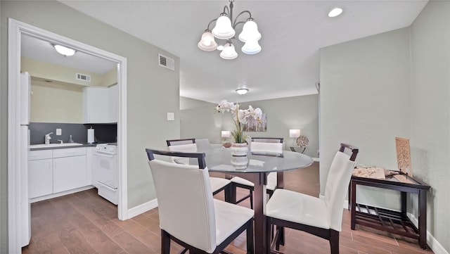 dining area with dark hardwood / wood-style flooring, a notable chandelier, and sink