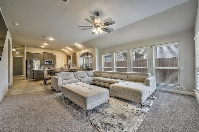 living room featuring ceiling fan, light wood-type flooring, and vaulted ceiling