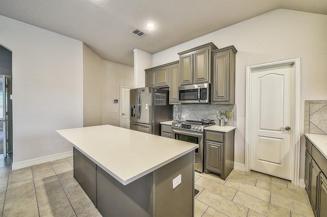 kitchen with a center island, backsplash, lofted ceiling, light tile patterned floors, and appliances with stainless steel finishes