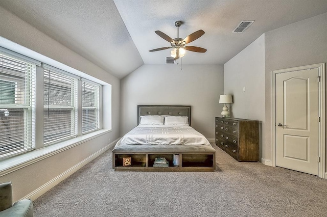 carpeted bedroom with ceiling fan, a textured ceiling, and vaulted ceiling