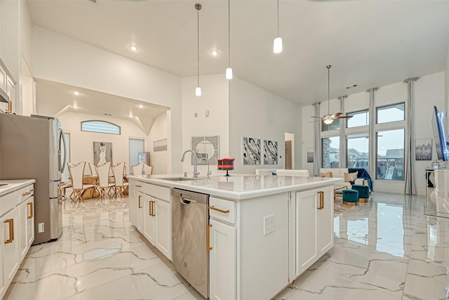 kitchen with stainless steel appliances, a kitchen island with sink, sink, pendant lighting, and white cabinetry