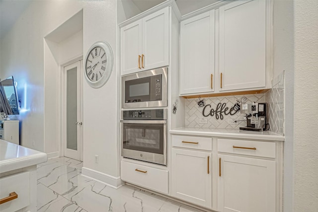 kitchen with white cabinetry, stainless steel appliances, and tasteful backsplash