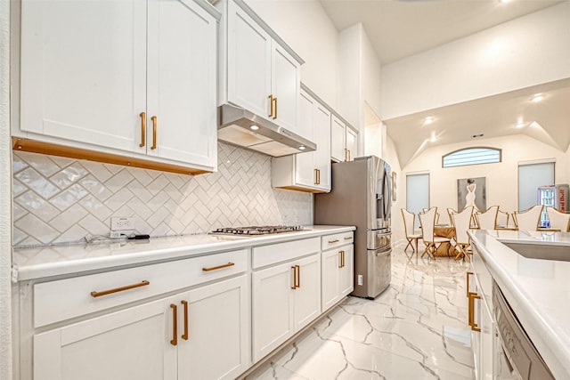 kitchen featuring vaulted ceiling, white cabinetry, appliances with stainless steel finishes, and tasteful backsplash