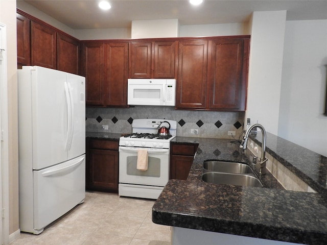 kitchen featuring white appliances, backsplash, sink, dark stone countertops, and kitchen peninsula