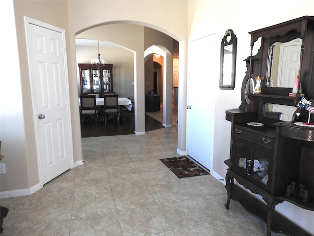 hallway with light tile patterned flooring and a chandelier