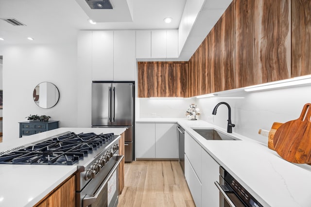 kitchen featuring appliances with stainless steel finishes, light hardwood / wood-style floors, white cabinetry, and sink