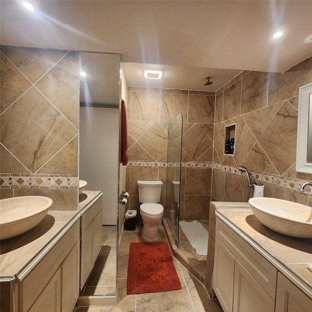 bathroom with vanity, toilet, tile walls, and walk in shower