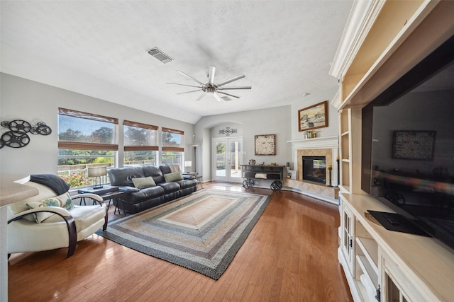 living room with hardwood / wood-style flooring, a fireplace, ceiling fan, and a textured ceiling