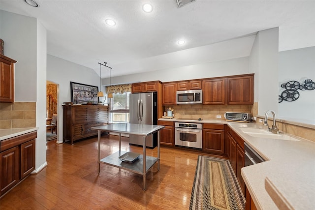 kitchen featuring appliances with stainless steel finishes, tasteful backsplash, sink, decorative light fixtures, and dark hardwood / wood-style floors