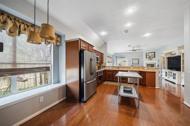 kitchen featuring ceiling fan, stainless steel appliances, dark hardwood / wood-style flooring, kitchen peninsula, and decorative light fixtures