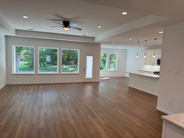 unfurnished living room featuring ceiling fan and dark wood-type flooring