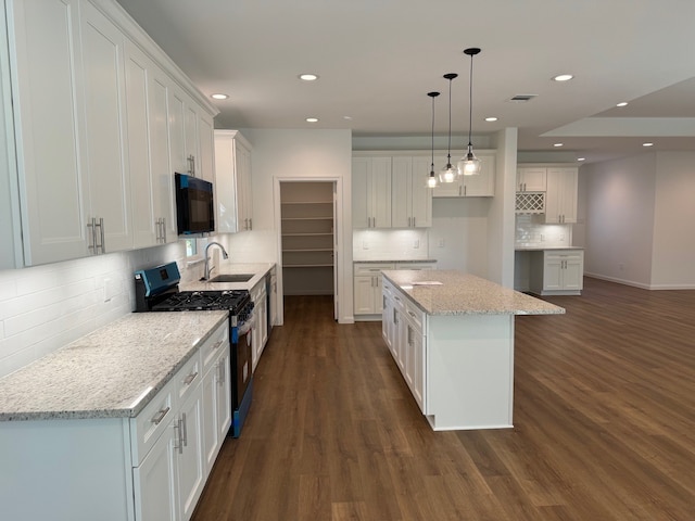 kitchen with sink, white cabinetry, a center island, hanging light fixtures, and stainless steel range with gas cooktop