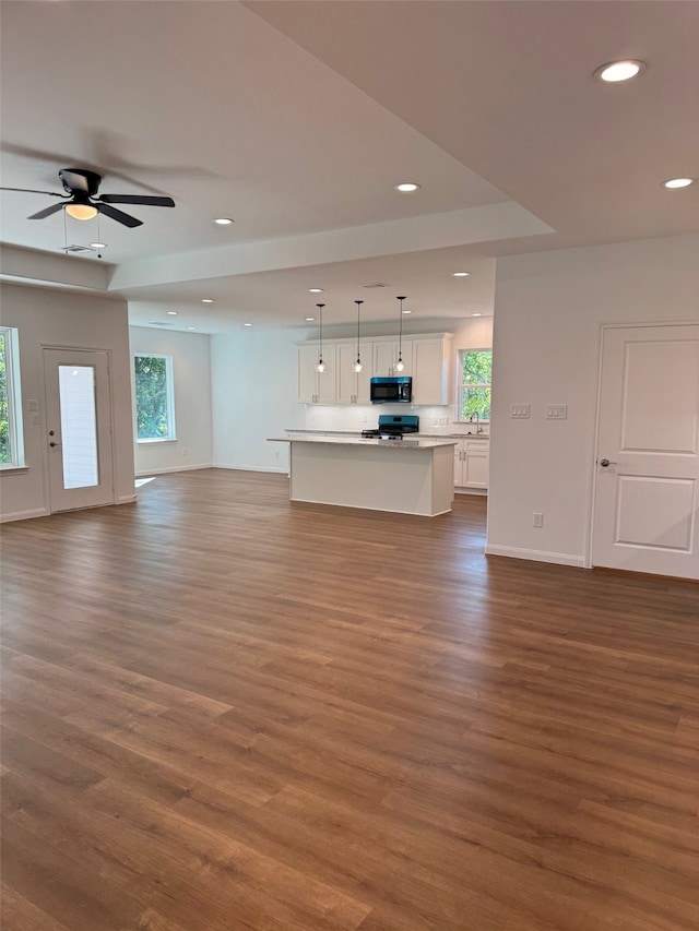 unfurnished living room with hardwood / wood-style floors, ceiling fan, and sink