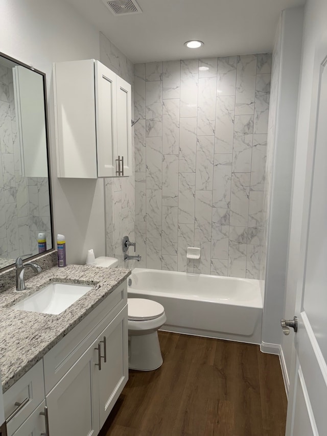 full bathroom with hardwood / wood-style floors, vanity, tiled shower / bath combo, and toilet