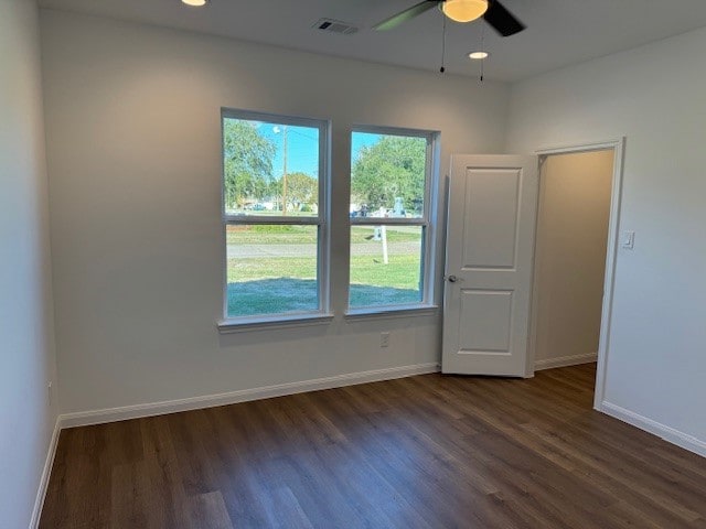 empty room featuring a wealth of natural light, ceiling fan, and dark hardwood / wood-style floors