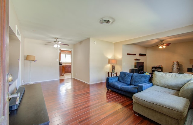 living room featuring ceiling fan and dark wood-type flooring