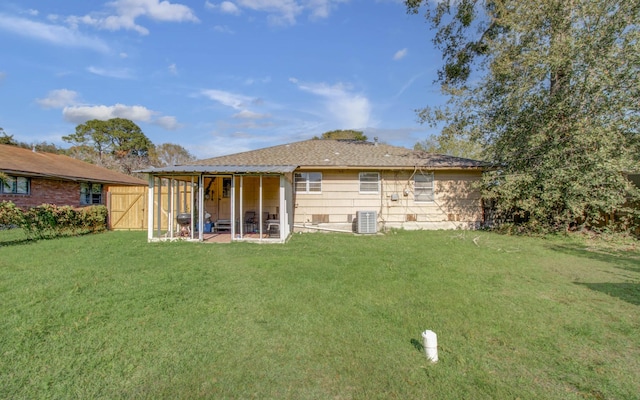 back of house featuring central AC unit and a lawn