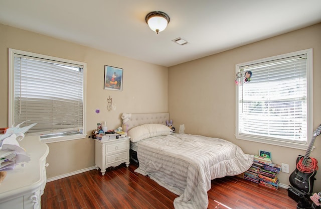 bedroom with dark hardwood / wood-style floors and multiple windows