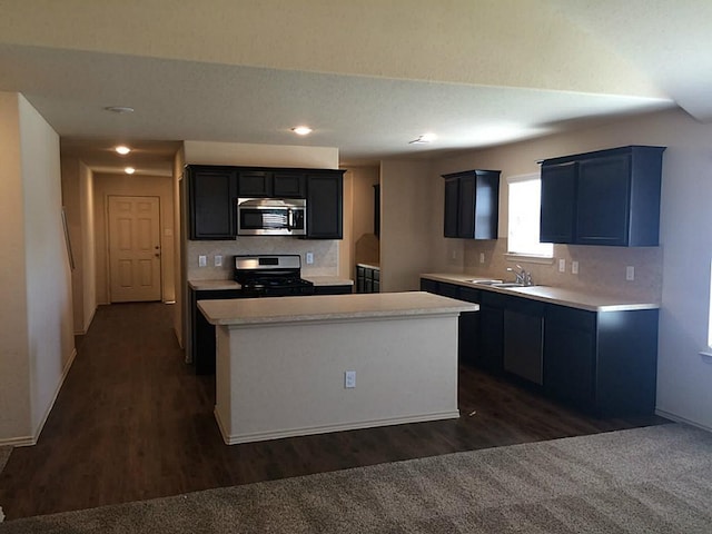 kitchen with a center island, dark wood finished floors, stainless steel appliances, light countertops, and a sink