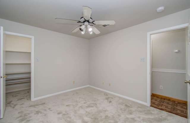 unfurnished bedroom with a spacious closet, ceiling fan, and light colored carpet