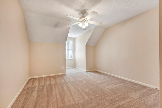 bonus room featuring a textured ceiling, light colored carpet, vaulted ceiling, and ceiling fan