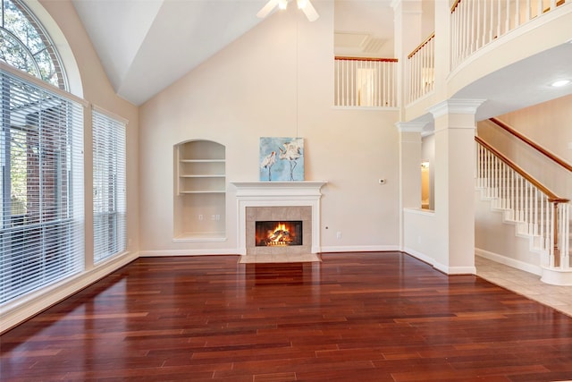 unfurnished living room featuring built in shelves, plenty of natural light, high vaulted ceiling, and dark wood-type flooring