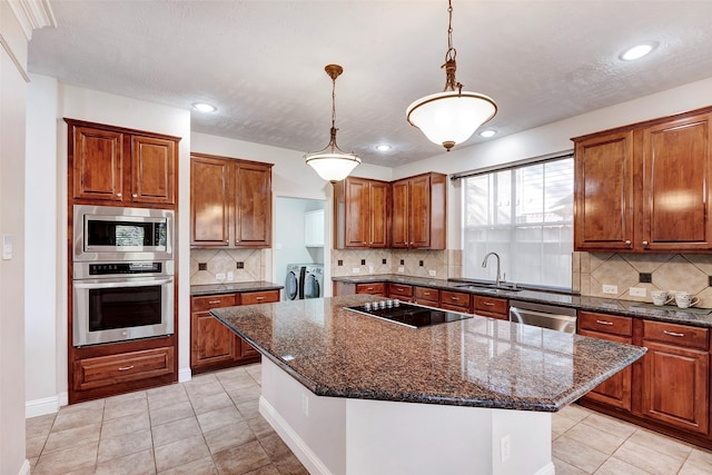 kitchen with washer and clothes dryer, decorative backsplash, a center island, and appliances with stainless steel finishes