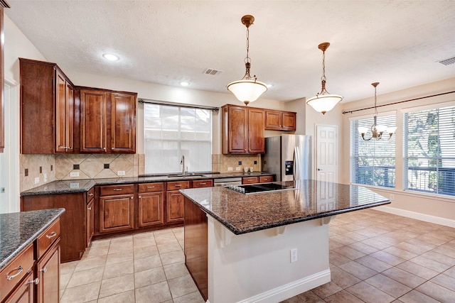 kitchen featuring stainless steel refrigerator with ice dispenser, a kitchen breakfast bar, sink, pendant lighting, and a center island