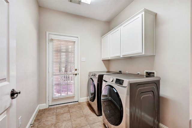 laundry room featuring washer and dryer, cabinets, and light tile patterned floors