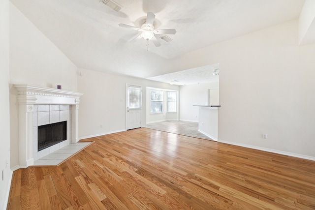 unfurnished living room featuring vaulted ceiling, a fireplace, light wood-type flooring, and ceiling fan