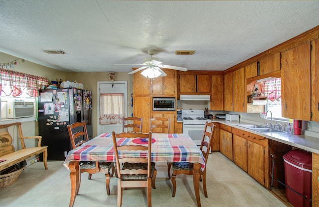 kitchen featuring gas range gas stove, stainless steel microwave, sink, a textured ceiling, and black fridge with ice dispenser