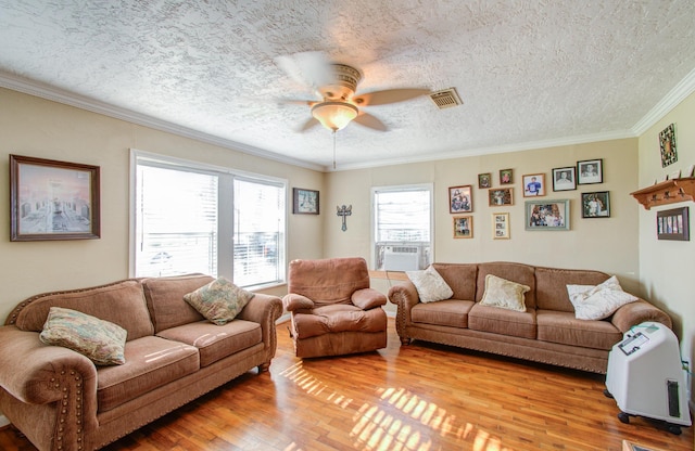 living room featuring ceiling fan, ornamental molding, hardwood / wood-style floors, and a textured ceiling