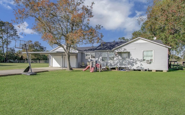 rear view of property featuring a yard, a garage, and a playground