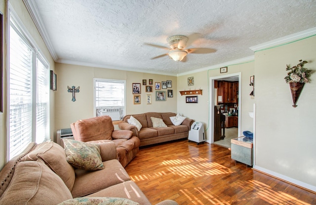 living room with hardwood / wood-style floors, cooling unit, ornamental molding, ceiling fan, and a textured ceiling