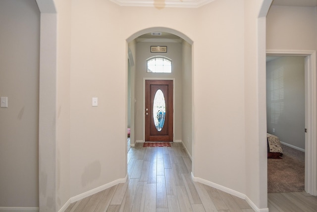 foyer entrance with light hardwood / wood-style flooring and ornamental molding