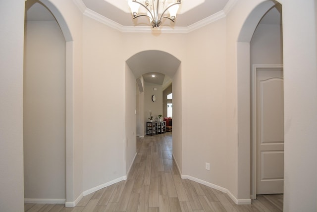 corridor featuring crown molding, light hardwood / wood-style flooring, and a chandelier