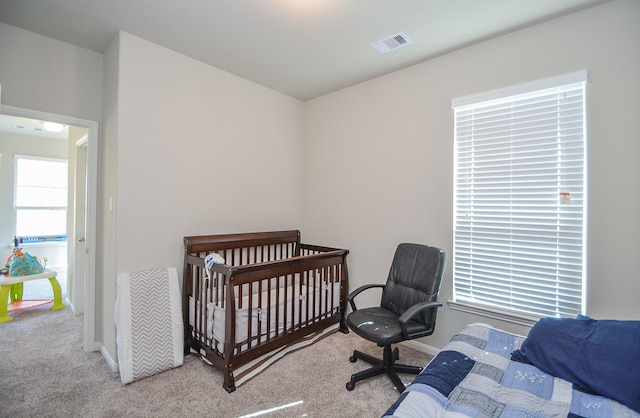 bedroom with light colored carpet and a nursery area