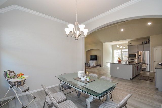 dining room featuring lofted ceiling, an inviting chandelier, sink, light hardwood / wood-style flooring, and ornamental molding