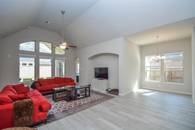 living room featuring ceiling fan with notable chandelier, a healthy amount of sunlight, lofted ceiling, and light hardwood / wood-style flooring