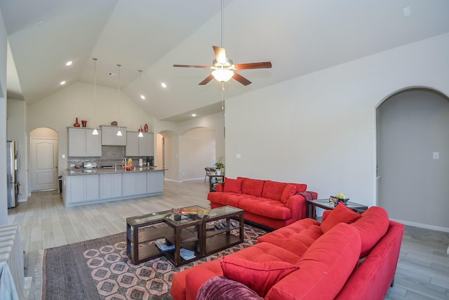 living room featuring light hardwood / wood-style floors, high vaulted ceiling, and ceiling fan