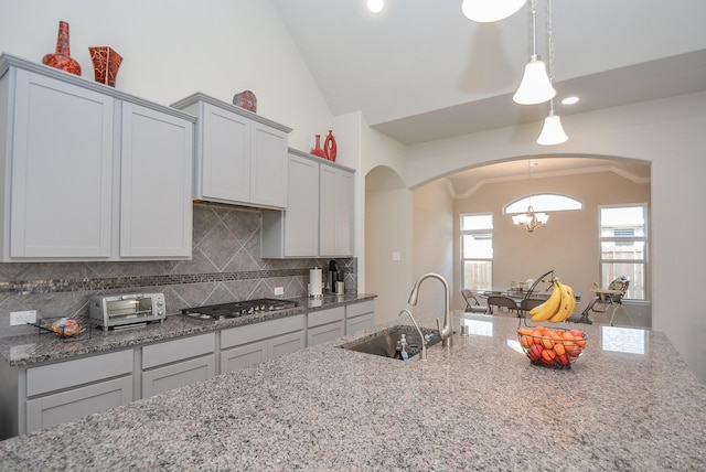 kitchen with sink, backsplash, decorative light fixtures, stainless steel gas stovetop, and ornamental molding