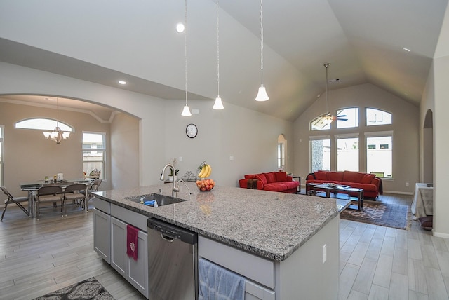 kitchen with sink, stainless steel dishwasher, pendant lighting, vaulted ceiling, and light hardwood / wood-style floors