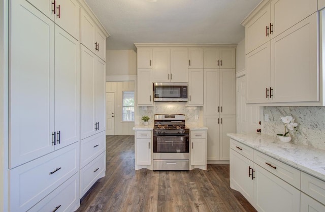 kitchen with dark hardwood / wood-style flooring, light stone countertops, appliances with stainless steel finishes, and tasteful backsplash