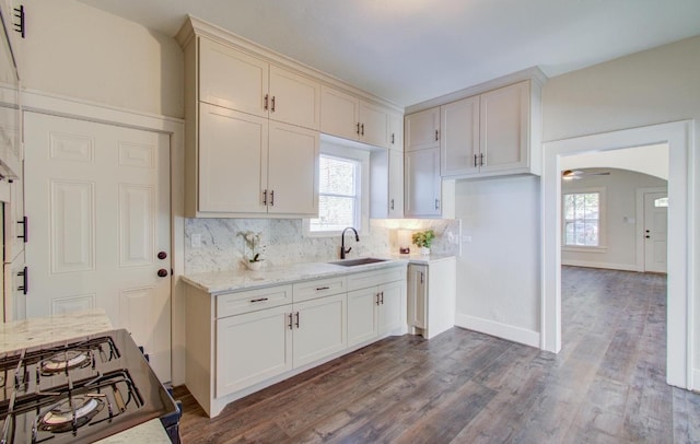 kitchen with light stone countertops, dark hardwood / wood-style flooring, tasteful backsplash, sink, and range