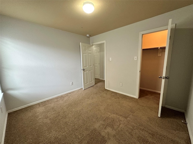 unfurnished bedroom with carpet flooring, a spacious closet, and a closet