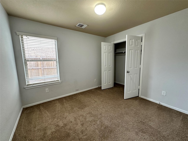 unfurnished bedroom with a textured ceiling, carpet floors, and a closet