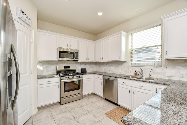 kitchen featuring appliances with stainless steel finishes, light stone counters, white cabinetry, and sink